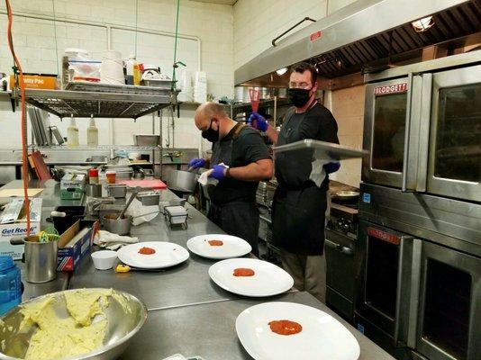 Chef and team in kitchen preparing for a plated tasting for clients.