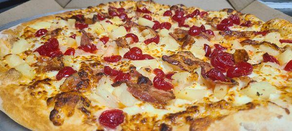 KJ's Hawaiian Tropic Pizza, loaded with ham, pineapple tidbits, bacon Garnished with maraschino cherries.