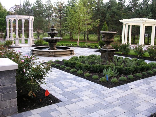 Formal garden in European flavor including granite gazebo, traditional garden ornaments, curved pergola and outdoor kitchen.