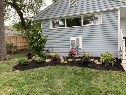 Created a landscape bed, consisting of trees and shrubs, finished with mulch and boulders.