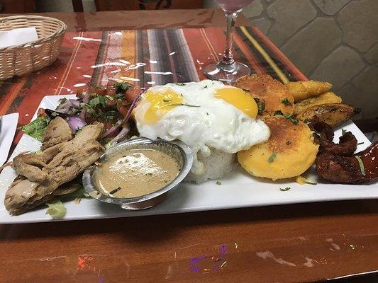 Yapingacho (potato cakes), served with a peanut sauce, with roast pig (hornado), salad, egg, rice, fried plantains, and chorizo.