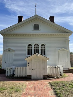 The Backside of the all white church, red brick driveway, green grass & trees @ Martha Mary Chapel @ Longfellow's Wayside Inn in Sudbury MA