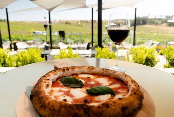 A classic margherita pizza with a perfectly charred crust, a glass of Akash malbec, and that view!