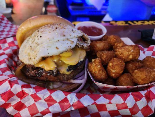 The works burger with an egg and tater tots