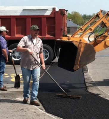 The new asphalt is carefully spread out and packed, then a final layer is added.