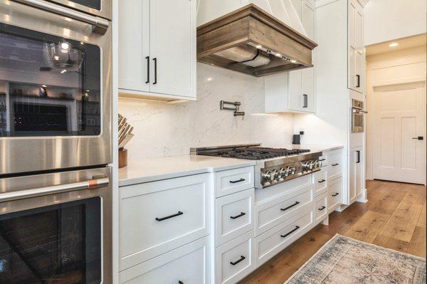 Kitchen cabinetry, quartz backsplash, and luxury vinyl flooring