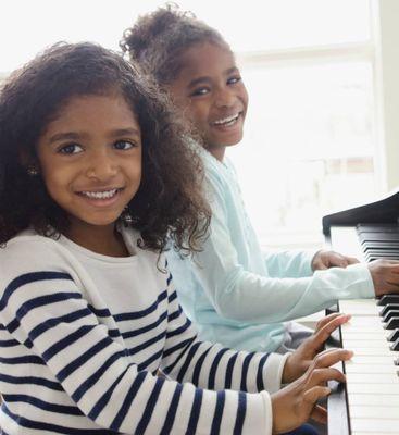 two younger kids taking piano lessons