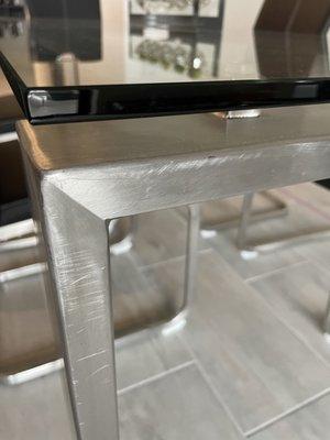 Stainless steel end of dining table base scratched because base was not wrapped and then stood on end in truck