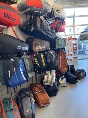 Wall of different styles and brands of tennis bags.