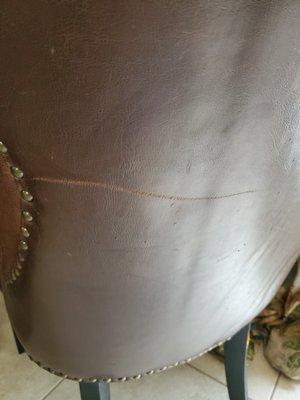 Large gouge on the back of a leather chair.