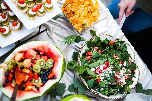 View of salad, potato chips, appetizers, and fruit at catering event