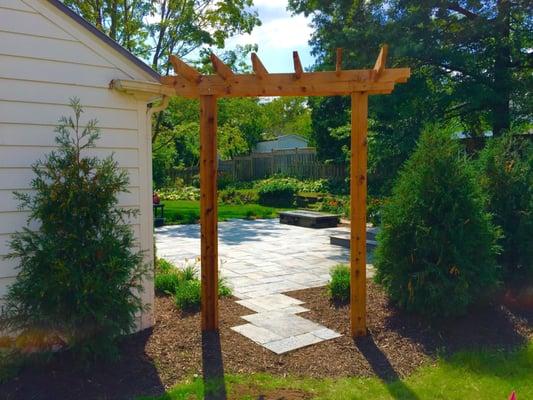 Cedar arbor entry to cut bluestone patio, with hot tub and custom built gas fire pit