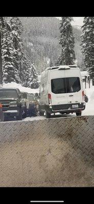 A Van trying to turn on ice and prevent hitting the parked cars.