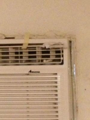 Holes around air conditioner. Tape holding together.