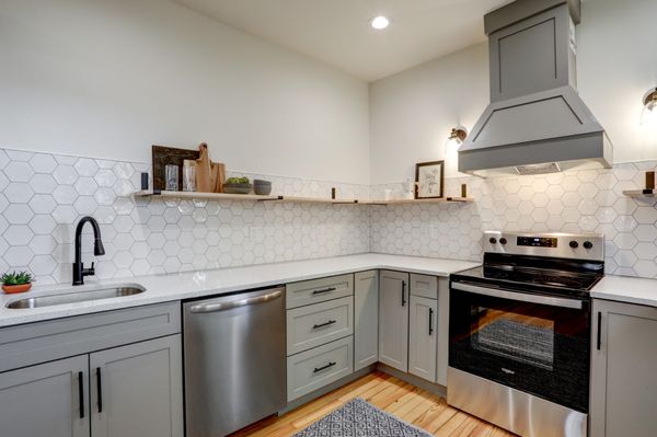 Kitchen design featuring gray shaker cabinets, hexagon backsplash, open shelving.