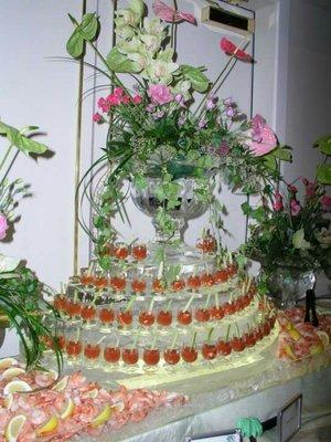 Stacked tiers of ice topped with an ice vase and flowers. Holes in ice precision cut to accommodate seafood shot glass hors d'oeuvres.