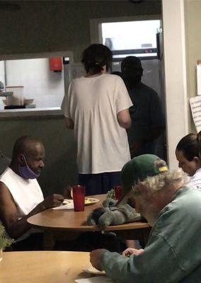 Same resident inside kitchen handing food to other residents