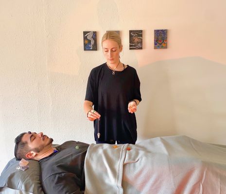 Sydney performing a pendulum reading to examine client's chakras as part of crystal healing add-on (FLIHH Holistic Wellness Studio- CA)