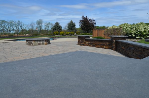 Sitting Wall, featuring natural stone facing with blue stone capping. 
 Fire pit repaired with blue stone capping.