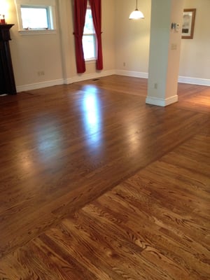 A stained oak floor that is located in a open layout downstairs, running in opposite directions.