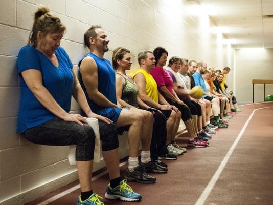 Metro42 Body Transformation Program participants doing a wall sit along the track.