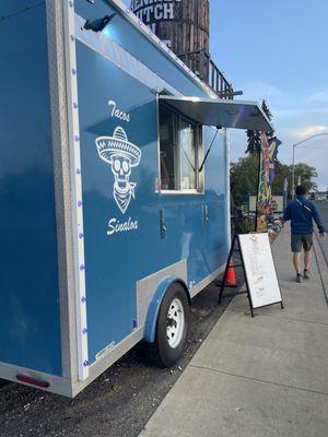 Food truck standing in front of sidewalk.