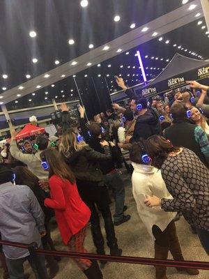 People enjoying silent disco = every one had on earphones listening to the music of their choice while on the dance floor with other people