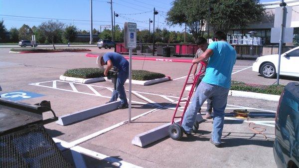 guys installing wheel stops to protect pole