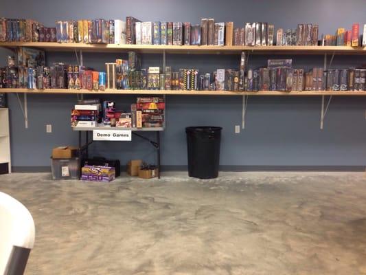 Shelves have a large assortment of games available for purchase.  Table has open copies of games to try and play.