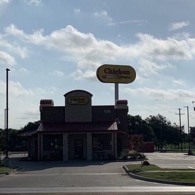 Front of Chicken Express with view of parking lot and sign.