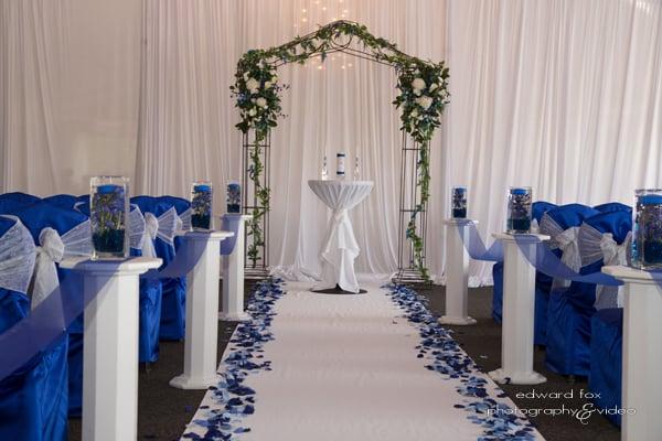 Ceremony at the Stonegate, Wide Cloth aisle runner with silk petals,wood stands down the aisle and archway decor.