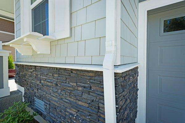 Charming details abound, with tasteful window shelves, matching shutters and trim work, including a gorgeous stacked stone half wall.