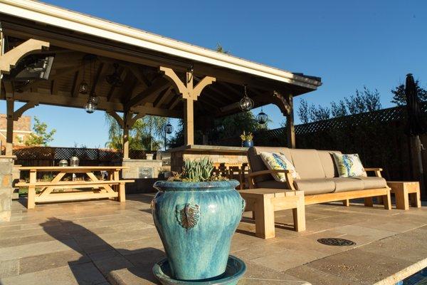 Outdoor kitchen with custom pergola, seating, and plant installation.