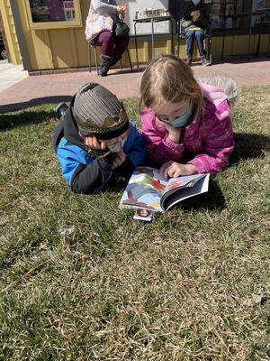 Two of the kids enjoying their books on the lawn outside the store.