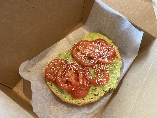 Decent avocado toast slice with tomato and sesame seeds.