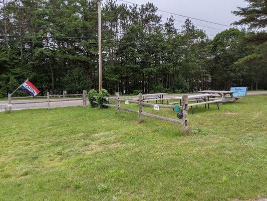 More outdoor picnic tables on the lawn above the road