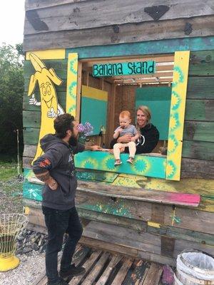 The owners holding a toddler at the banana stand.