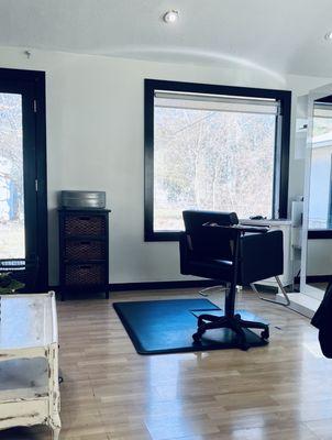 This is Megan's hair station with a beautiful window that lets in sunlight and overlooks beautiful trees.