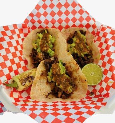 Savor a succulent carne asada taco topped with a generous dollop of freshly made guacamole. The guacamole is a creamy blend of ripe avocados