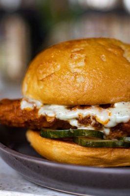 Buffalo Chicken Sandwich | breaded chicken tenders tossed in buffalo sauce, housemade pickles, grilled bun, bleu cheese aioli (GF available)