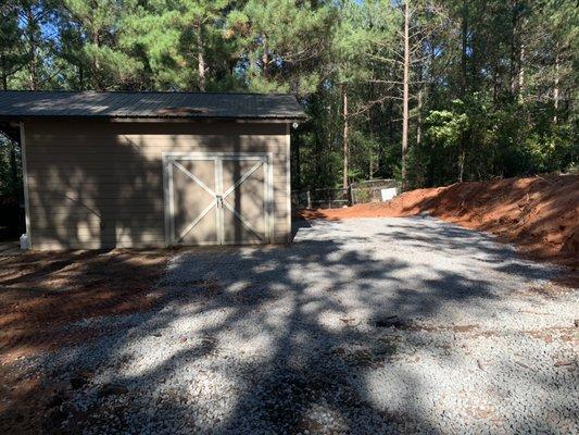 Removed a hill of dirt next to a storage building  and added a pad for parking