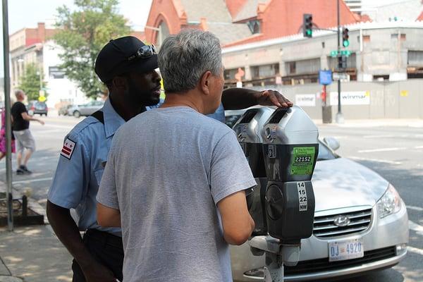 DC DPW Parking Enforcment Worker assists two men with parking meter at 14th near Q Street, NW, Washington DC on 2 August 2012.