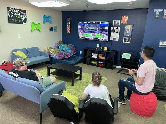 Kids in teen room watching a video game on big tv.