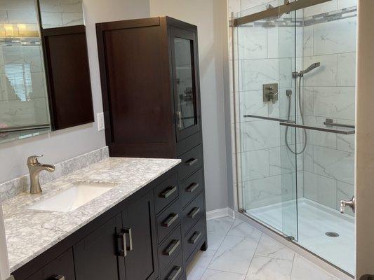 Renovated master bath; angular wall removed to make room for linen tower. Polished porcelain tile in shower; matching matte tile on floor.