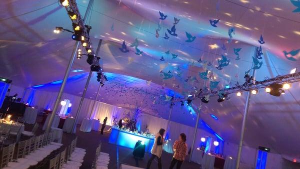 6,000 square foot tent transformation with flown lighting for decorative design and runway show. Custom lit bar and overhead decor.