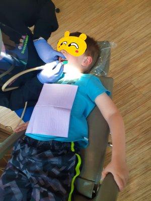 My son getting a teeth cleaning. They do a great job. He's not actually wearing an eye mask; I've just added this for child privacy.