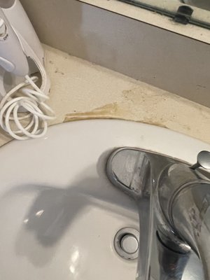 Bathroom counter behind sink not cleaned