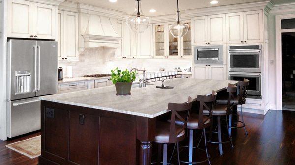 White kitchen with stainless steel refrigerator and island remodeled by Diamond Builders of America, Inc.