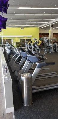 Another row of cardio machines, with a window view and televisions.