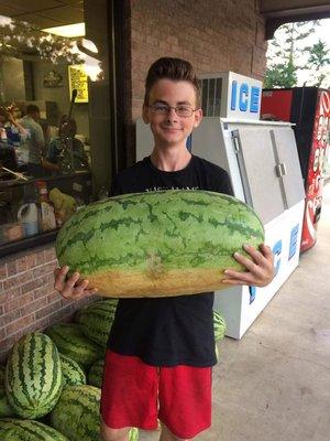 Owners son holding one of the largest watermelons in July... Yum